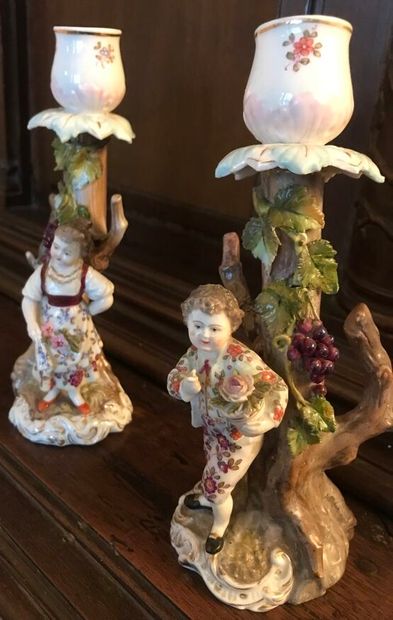 null *Paire de BOUGEOIRS en porcelaine figurant un couple accoudé sur un décor aux...