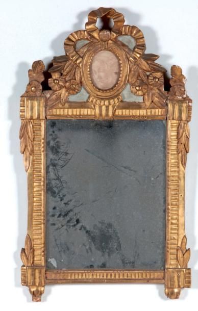 null MIROIR en bois sculpte et dore somme d'un fronton au noeud rubanne, fleurs et...