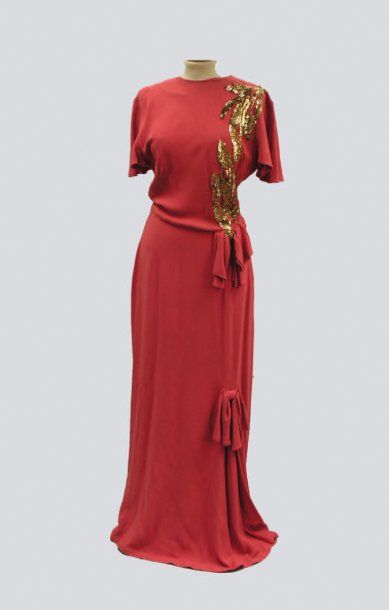null Une robe du soir en crêpe corail, à motifs pailletés or. Vers 1930.