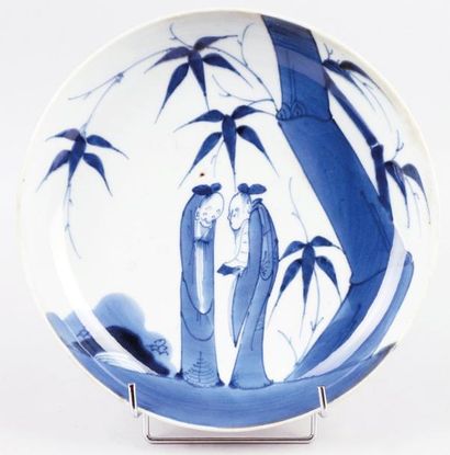 JAPON, XIXe siècle PLAT en porcelaine blanc-bleu à décor de personnages conversa...