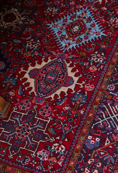 null * Grand tapis en laine à fond rouge à décor de fleurs stylisées et larges cartouches...