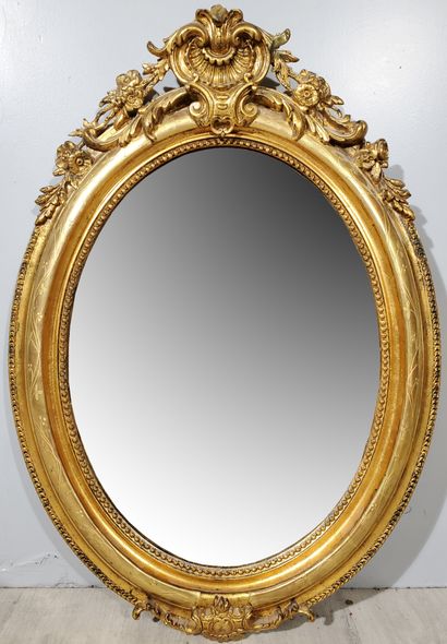 null Oval-shaped MIRROR, wood and stucco with gilded patina, string of pearls and...