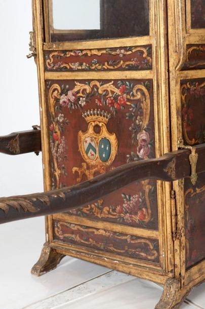 null Une chaise à porteurs Louis XV en bois doré à décor rocaille, reposant sur des...