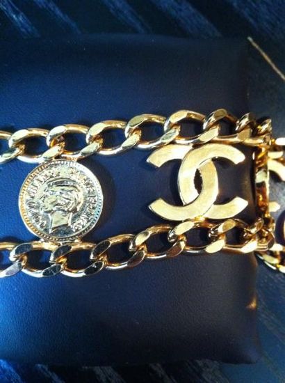CHANEL Gourmette en métal doré orné de pièces à l'effigie de Coco Chanel et de "CC"...