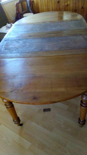 null Une table ronde en bois naturel à système d'allonges reposant sur cinq pieds...