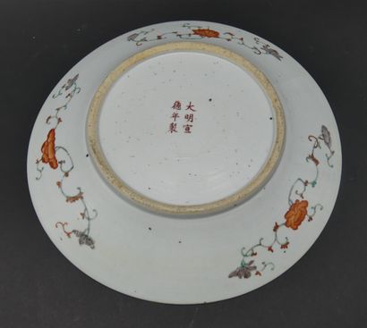null A round porcelain and polychrome enamel dish decorated with three dragons chasing...