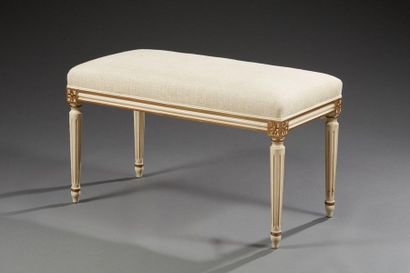 null Un banc de style Louis XVI en bois laqué rechampi doré, garni d'une toile ecrue...