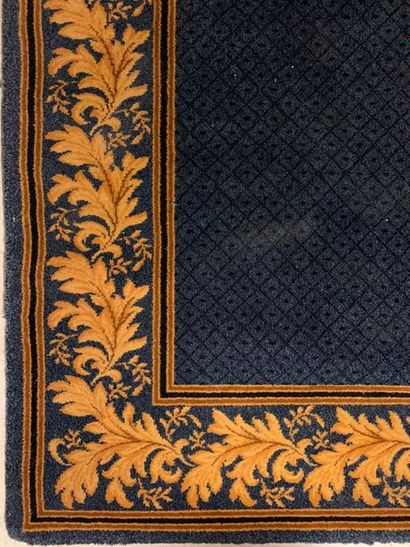 null Une carpette en moquette rectangulaire à fond bleu, bordure de rinceaux feuillagés...