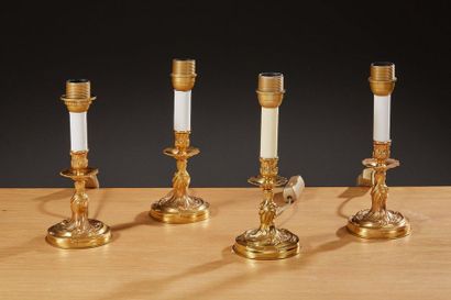 null Suite de quatre petits flambeaux en métal doré de style Louis XV. 

Hauteur...