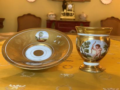 null Tasse et sa sous-tasse en porcelaine polychrome et dorée à décor d'un putti...