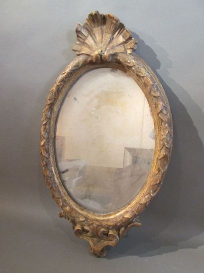 null Miroir ovale en bois sculpté et doré à décor d'une coquille et frise feuillagée....