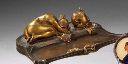 null Encrier en bronze patiné et doré à décor d'une femme allongée à coté d'une pomme.
Porte...