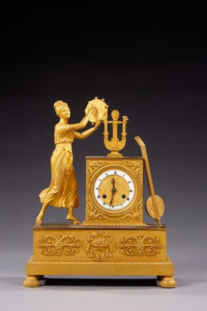 null Pendule en bronze ciselé et doré à décor d'une femme à l'Antique jouant du tambourin,...