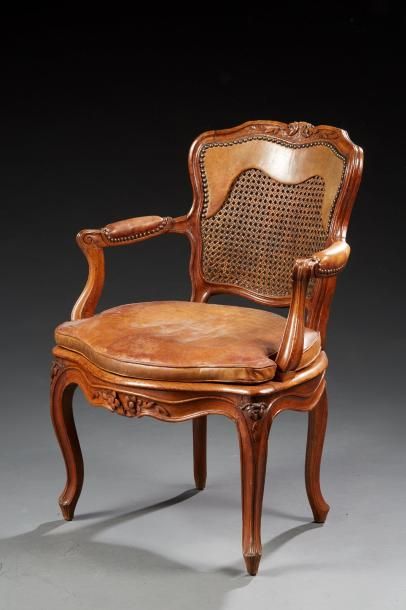 null Un fauteuil de style Louis XV en bois naturel sculpté de fleurettes et reposant...