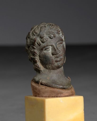  Tête d’éphèbe du type d’Antinoüs, à la chevelure composée de ﬁnes mèches. 
Bronze...