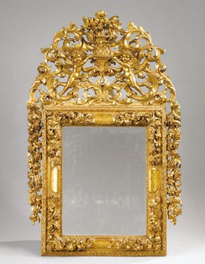 null MIROIR à encadrement de bois doré et sculpté, fronton aux putti et chutes en...