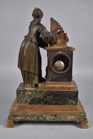 null Pendule en bronze ciselé à double patine à décor d'une femme jouant de l'orgue,...
