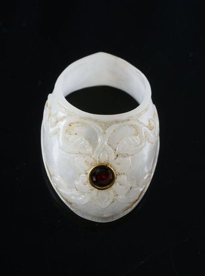 null Bague d'archer en néphrite ciselé d'un décor de fleur et ornée d'un grenat serti...