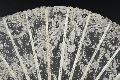 null Luxuriance, circa 1890
Fan, the leaf in needle lace, cream-coloured, with rich...