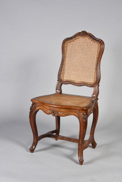 null A suite of eight caned chairs in moulded and sculpted natural walnut, they rest...