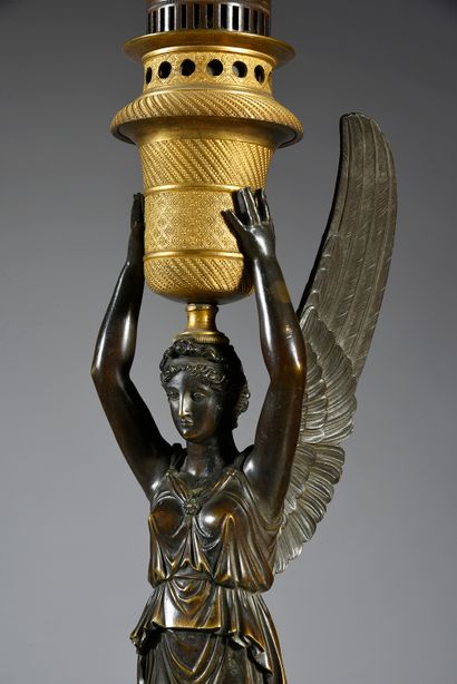 null A pair of lamps in patinated and gilt bronze, formed by a winged victory supporting...