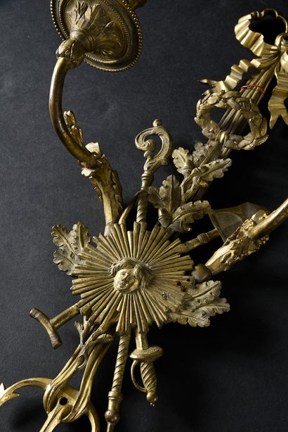 null A pair of two-light sconces in chased and gilded bronze, a ribbon knot holding...