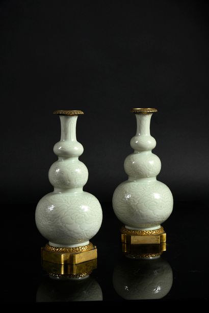 null A pair of celadon embossed porcelain triple gourd vases, decorated with peonies...