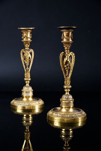 null Pair of chased and gilded bronze candlesticks, the circular base with acanthus...