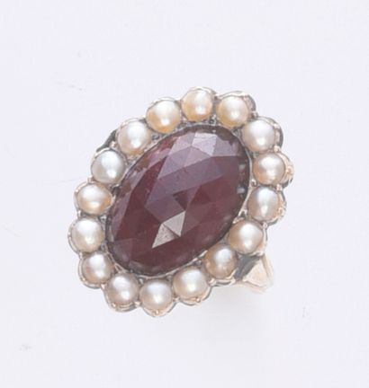 null 585th gold ring set with an oval rose-cut garnet on a pearl, surrounded by half...