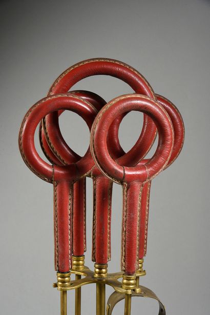JACQUES ADNET (1900-1984) Nécessaire de cheminée en laiton et cuir rouge à piqué...