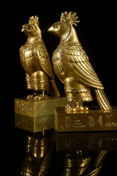 null Pair of falcons in chased and gilded bronze, they rest on a rectangular base...