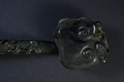 CHINE, XIXe siècle Sceptre ruyi en jade épinard
Sculpté en relief dans le goût naturaliste,...