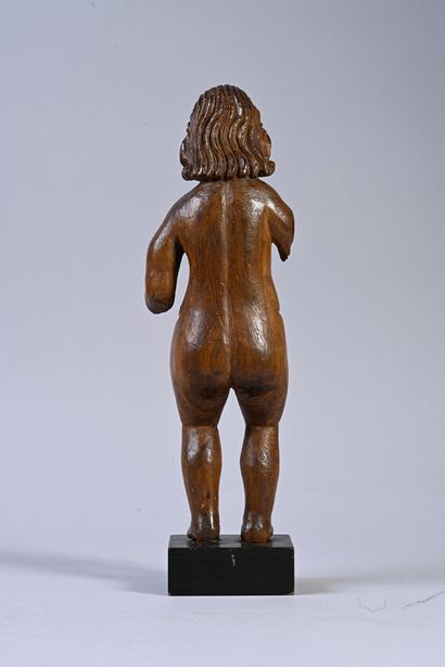 null Wooden child sculpted in the round. Standing naked, the Child has long wavy...