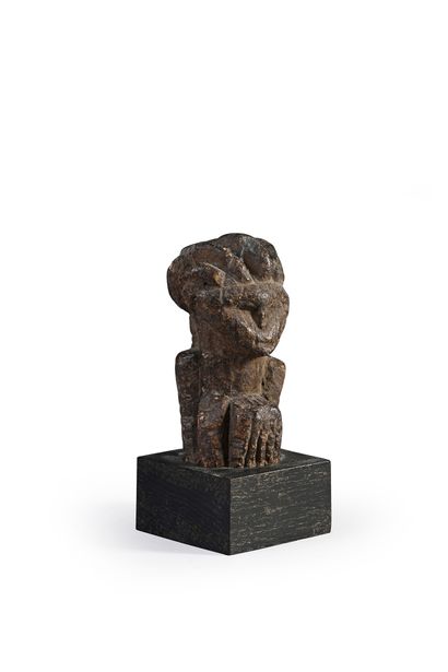 null Small female statuette with a curled up body, presenting a face with an angular,...