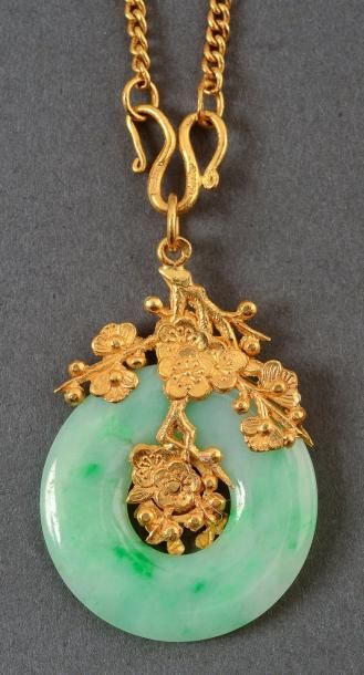 null Un pendentif en or jaune, maintenant un disque de jade dans un motif floral....