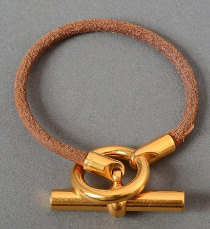 HERMES Bracelet cordon de cuir terminé par un fermoir en métal dor. boucle et bâtonnet....