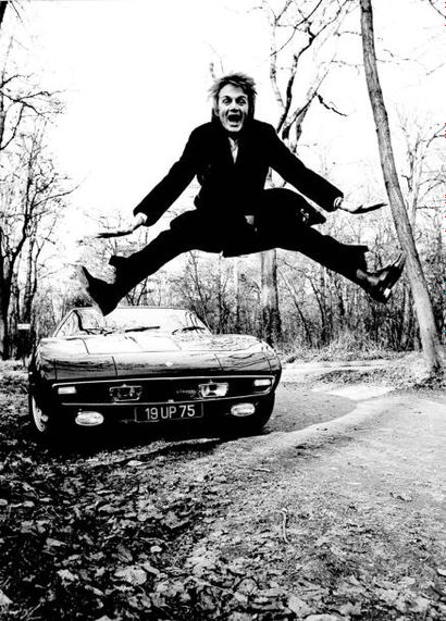 Tony Grylla Claude François sautant devant sa Maserati Ghibli. 1969. Photographie...
