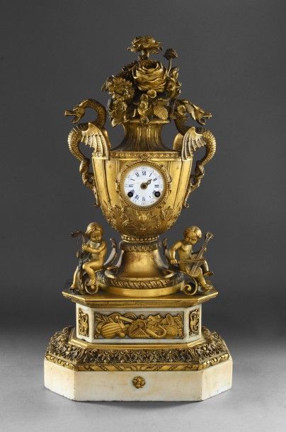 null Pendule en bronze doré et marbre blanc, à décor d'un vase fleuri, les anses...
