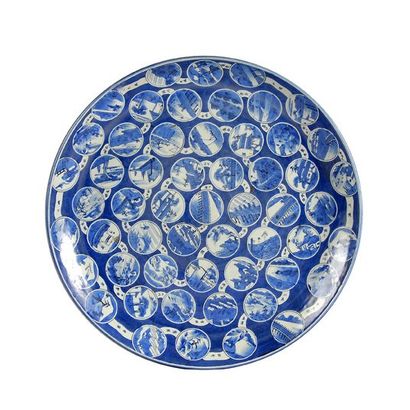 JAPON Important plat en porcelaine à décor blanc et bleu de vignettes ronde. (Cheveux)...