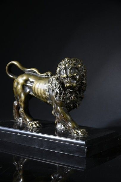 null Statuette en bronze patiné représentant un lion marchant, tête tournée, reposant...