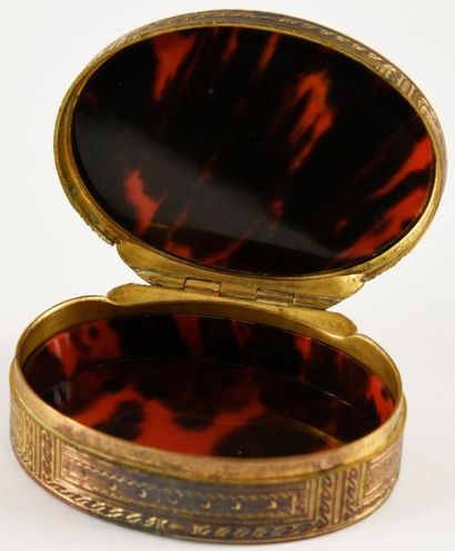 null Boîte ovale en laiton doré, à décor guilloché de raies, de perles et de motifs...