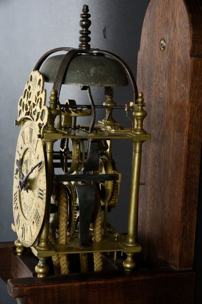 null A melted and engraved brass lantern clock, it rests on four ball feet, the Roman...