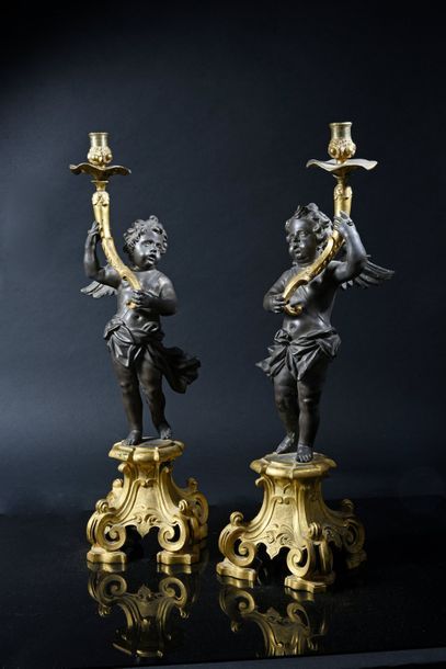 null Pair of chased bronze candelabra, patinated and gilded, featuring angels holding...