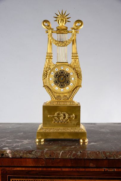  Pendule lyre en bronze ciselé et doré. Pieds galettes, base ornée de couronnes laurées...