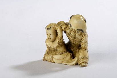 null Netsuke en ivoire à patine jaune, deux karako accroupis, l'un portant un masque...