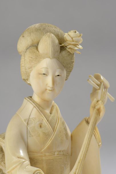 null Okimono en ivoire, jeune femme jouant du shamisen, son kimono très finement...