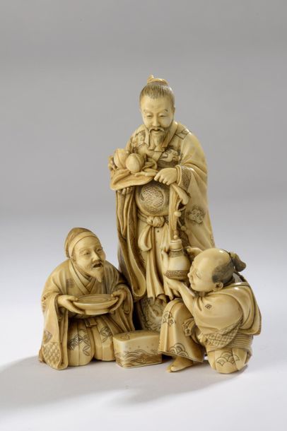 null Okimono en ivoire à patine jaune, trois personnages dont un taoïste qui tient...