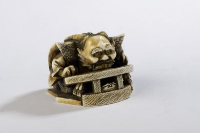 null Netsuke en ivoire, personnage cornu penché sur un écritoire, un éventail à terre.
Signé...