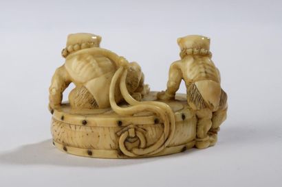 null Netsuke en ivoire, deux onis juchés sur un tambour à décor de tomoe.
Les himotoshi...