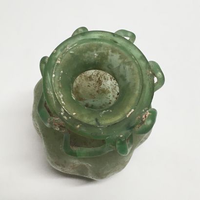 null A green glass aryball with a depressed body and a sawtooth-shaped net applied...